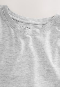 Camiseta gris de manga corta con cuello redondo, fabricada en un tejido suave y texturizado, que presenta un sutil patrón jaspeado y una etiqueta de marca visible en el interior.