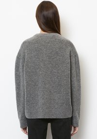 Maglione grigio a maglia con scollo tondo, spalle scese e polsini a costine. Tessuto morbido, vestibilità rilassata e orlo leggermente accorciato.
