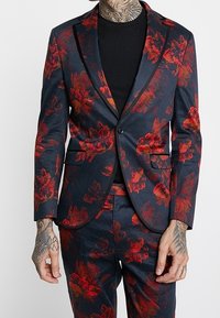 Blazer floreale in blu navy scuro, con motivi di foglie rosse e arancioni, design aderente, revers a punta e due tasche anteriori.