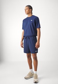 Completo abbinato blu navy composto da una t-shirt a maniche corte e pantaloni corti con cordino, realizzato in tessuto morbido con un piccolo logo bianco.