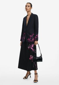 Tengerészkék blézer rózsaszín virágmintával, hosszú, fekete szoknyával, hasonló hímzéssel párosítva. Fekete válltáska, fekete magassark�ú cipő. Simább textúrák.