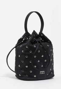 Bolso tipo cubo de nailon negro con tachuelas plateadas, cierre con cordón ajustable, dos asas cortas y logo en la base. Forma redonda y textura suave.
