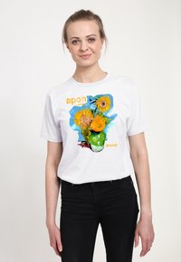 Bílé bavlněné tričko s barevným obrazem slunečnice, s nápisem „apoh London“ a „Vincent“ v tučných, živých barvách.