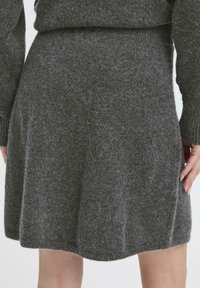 Gonna grigia lavorata a maglia, realizzata in un morbido misto lana testurizzato, con un design svasato e una vita a coste, che arriva a metà coscia.