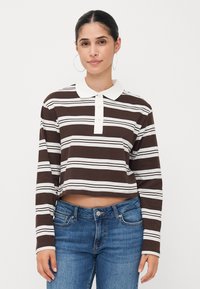 Brun og hvit stripete langermet polo shirt med hvit krage og tre knappelukking, kombinert med blå denimjeans.