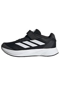 Zapatillas deportivas negras con acentos blancos, que cuentan con una parte superior de malla texturizada, una correa de velcro, una suela ligera y un destacado diseño de tres rayas.