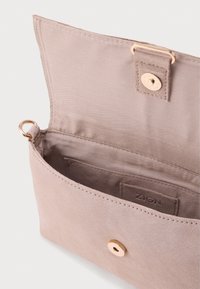 Φωτεινό τσάντα χειρός σε απόχρωση ταούπ από μαλακό υλικό, με χρυσό κούμπωμα, εσωτερική τσέπη και ανάγλυφο λογότυπο της μάρκας.