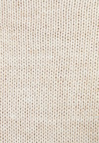 Pletená látka v svetle béžové barvě s texturovaným vzorem. Disponuje měkkou a mírně elastickou tkaninou, která vytváří hladký povrch.