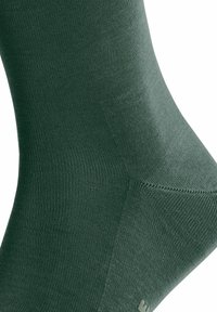 Calcetín de tobillo verde hecho de material texturizado, con un diseño acanalado que incluye puntera y talón reforzados, y un acabado sin costuras.