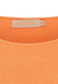 Orange strikbluse med rund halsudskæring. Et mærke med "MARTA" i guldfarve er synligt på kraven. Struktureret stof.