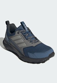Blå og grå atletiksko med mesh-overdel, teksturerede syntetiske overlays, polstret krave og gummisål. Har snørebåndsdesign og strop.