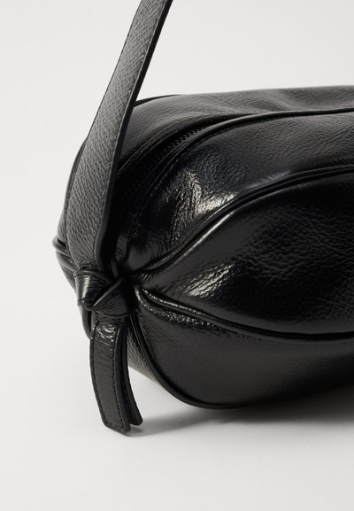 Borsa a tracolla in pelle nera con una finitura liscia e lucida, forma arrotondata e dettaglio di chiusura con tracolla annodata. Nessun hardware visibile.
