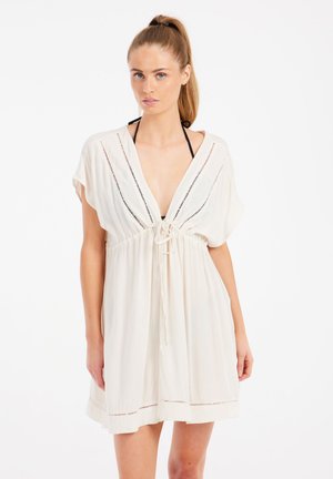 Robe de couverture légère de couleur crème. Décolleté en V, manches courtes, cordon de serrage à la taille et coutures décoratives le long de l'ourlet et de l'encolure.