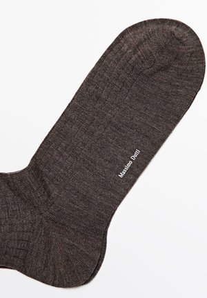 Brąsocka w kolorze brązowym z prążkowaną strukturą. Posiada logo wydrukowane na biało, umieszczone po boku w pobliżu łuku. Okrągły kształt palców.