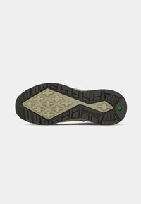 Podrážka topánky má čierny gumový dizajn s béžovým vzorovaným medzipodrážkou, zdobená hexagonálnymi tvarmi a vyrazeným logom "Timberland".