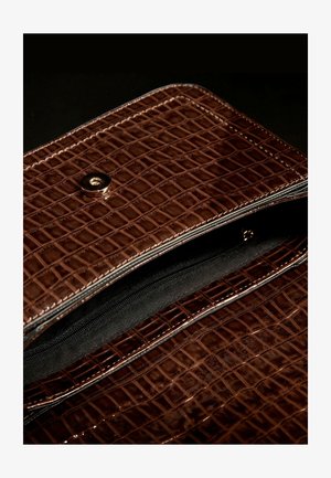 Sac à main en cuir embossé croco marron avec quincaillerie dorée, doté d'une fermeture à pression et d'un intérieur en tissu noir avec une poche zippée.