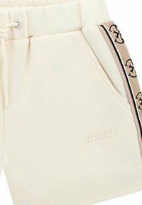 Shorts en mélange de coton beige avec taille élastique et cordon de serrage, dotés de poches latérales et d'une bande latérale marron embossée du logo.