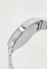 Montre-bracelet en acier inoxydable avec un boîtier rond, une couronne texturée et une finition lisse et polie, accompagnée d'un bracelet à maillons.