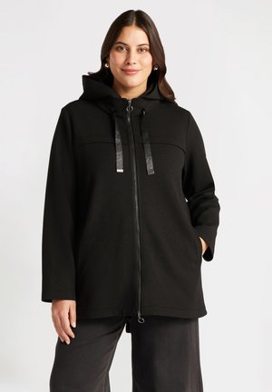 Giacca nera con cappuccio e zip frontale, dotata di due tasche frontali, tessuto texturizzato e lacci riflettenti sul cappuccio.