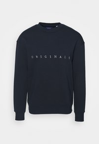 Námořnická mikina vyrobená z bavlny s kulatým výstřihem a volným střihem. Na přední straně je v bílé barvě potisk "ORIGINALS". Rybářské manžety a lem.