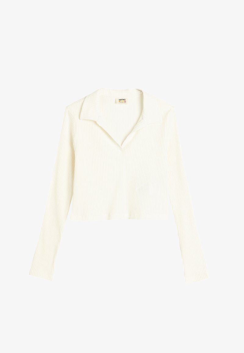 Valkoinen ribattu pitkähihainen lyhyt paita, jossa on lovikaulus. Pehmeä rakenne, jossa on pystysuuntaiset raidat ja rento istuvuus. Tunnus näkyvissä kauluksessa.