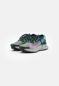 Chaussures de sport avec une tige en mesh vert et noir, dotées d'un swoosh violet, d'une semelle intermédiaire mouchetée et d'accents bleu sarcelle. Semelle extérieure en caoutchouc noir.
