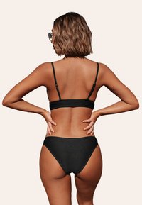 Conjunto de bikini negro de canalé que incluye un top bandeau texturizado con tirantes ajustables y braguitas de cintura alta, apto para bañador.