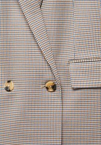Veste à motif pied-de-poule marron, bleu et blanc avec deux boutons marron et un rabat de poche poitrine sur le côté droit.