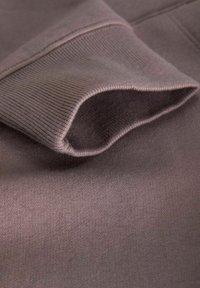 Brown fabric with a soft texture, featuring a ribbed cuff. The material is lightweight and smooth, with subtle stitching details.