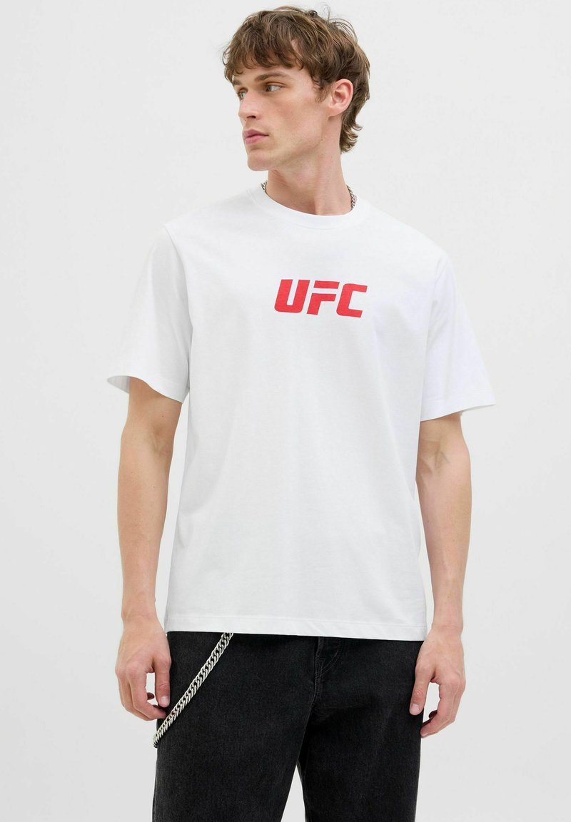 Fehér pamut póló, amelyen egy kiemelkedő piros "UFC" logó található merész betűtípussal. Rövid ujjú és klasszikus kerek nyakkivágású.