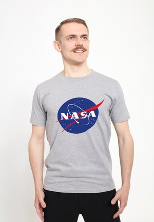 Grauem Baumwoll-T-Shirt mit einem NASA-Logo, das einen blauen Kreis, weiße Schriftzüge und rote Akzentgrafiken zeigt, präsentiert an einem Model.