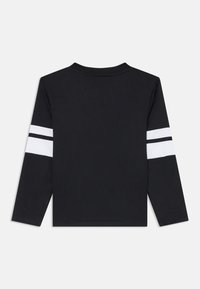 Chemise noire à manches longues avec des rayures blanches sur les manches, mettant en avant un col rond et un tissu lisse. Design simple et moderne sans détails supplémentaires.