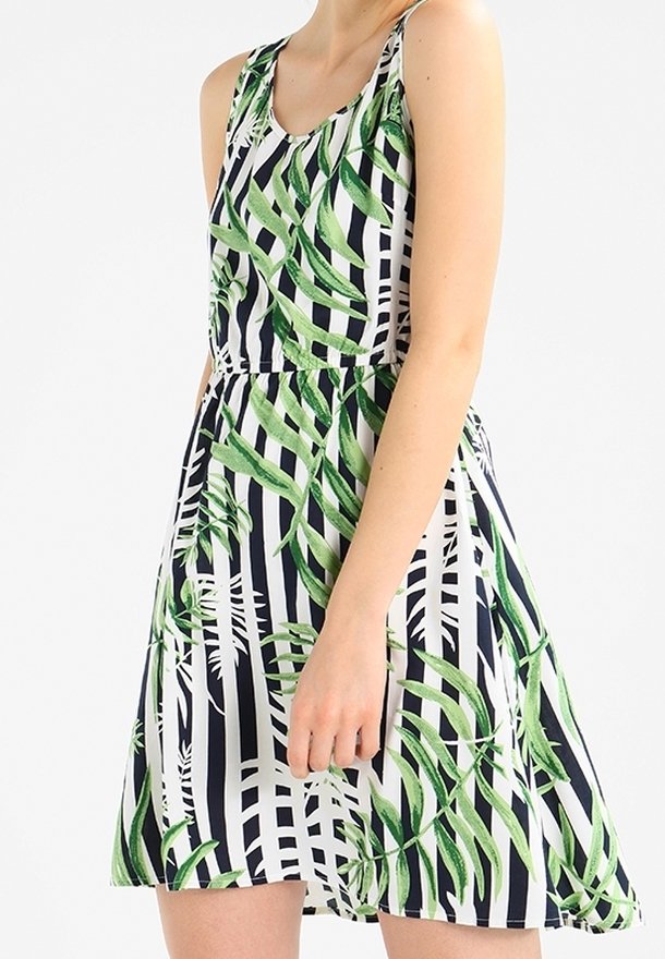 Robe sans manches présentant un motif de feuilles vertes sur un fond rayé bleu marine et blanc, avec une taille ajustée et une jupe évasée.