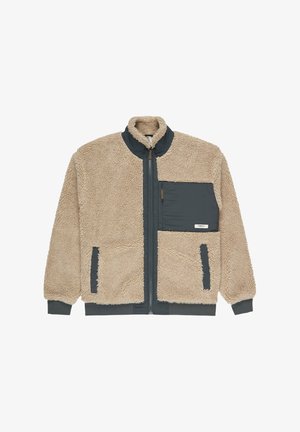 Beige faux furjakke med lynlås foran, høj krave og mørkegrå nylon detaljer. Har to frontlommer og en lomme på brystet.