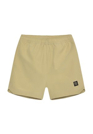 Beige, dehnbare Shorts mit elastischem Bund, seitlichen Taschen und einem kleinen schwarzen Etikett am linken Bein. Glatter Stoff und figurbetonte Passform.