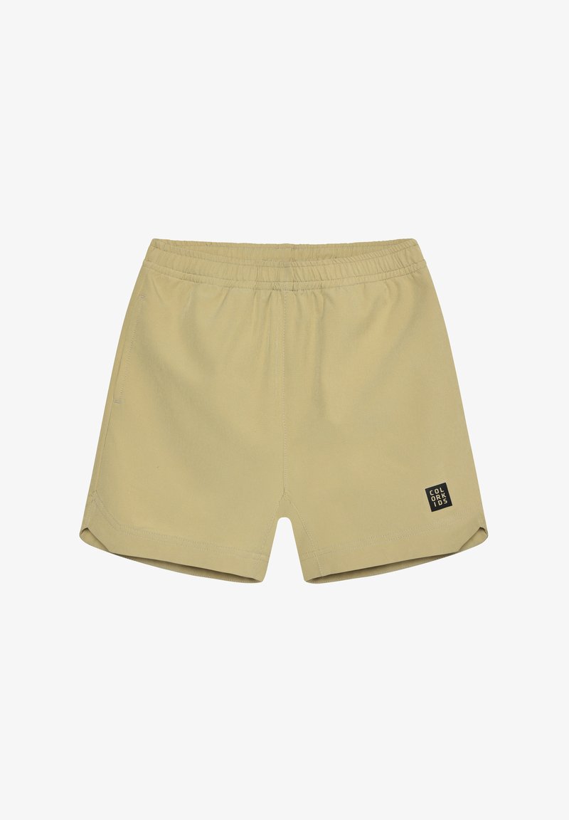 Pantalones cortos beige elásticos con cintura elástica, bolsillos laterales y una pequeña etiqueta negra en la pierna izquierda. Tela lisa y ajuste entallado.