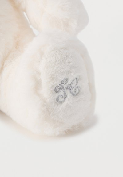 Απαλή λευκή μαλακή πατούσα παιχνιδιού με ασημένια κεντημένα αρχικά «fb» σε απλό λευκό φόντο.