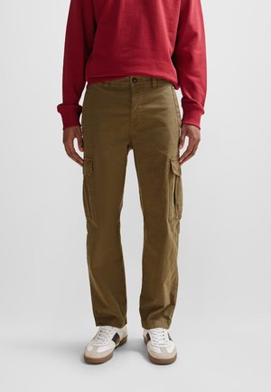 Khaki Cargo-Hosen mit zwei Seiten Taschen, einer regulären Passform und einer leicht gebürsteten Textur, kombiniert mit einem roten Langarm-Sweatshirt.