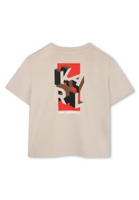Beige katoenen t-shirt met een grafisch ontwerp met 3D letters "KARL" in zwart en bruin op een rode achtergrond. Merktekst aan de onderkant.