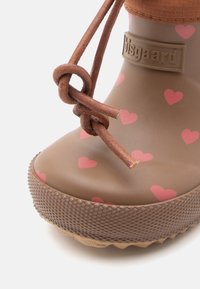 Brune gummistøvle med pink hjerte mønster, tekstureret sål, og en brun knyttet læderaccent øverst. Brandlogo synligt på siden.