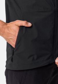 Schwarze leichte Jacke mit einer Reißverschlusstasche an der Taille, die über eine glatte Textur und ein minimalistisches Design verfügt. Mit Akzentnähten.