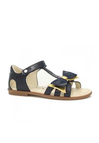 Sandalo in pelle verniciata blu navy con cinturino regolabile, caratterizzato da un grande fiocco decorativo con riflessi lucidi e metallici in oro.