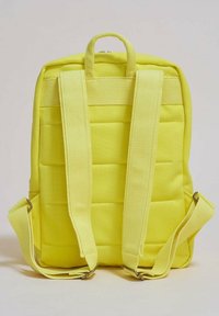 Gul ryggsäck tillverkad av vadderat tyg, med justerbara remmar och ett handtag på toppen. Slät textur med dragkedjestängning.