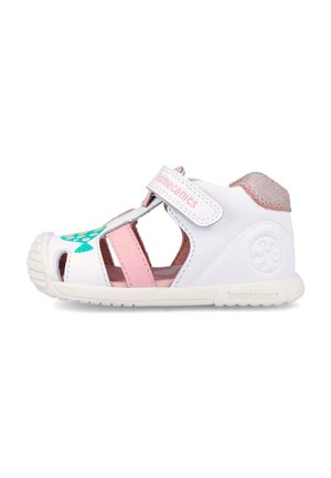 Sandalia para niño pequeño en blanco y rosa con suela de goma, cierre de velcro, diseño de pez en la punta y cuello acolchado en el talón.