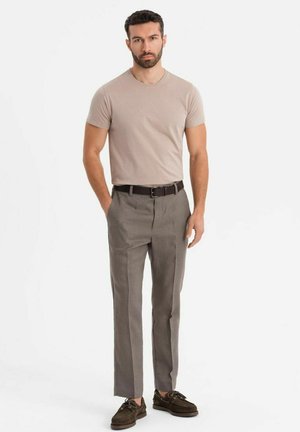 Camiseta beige, pantalones grises ajustados y zapatos marrones. Los pantalones tienen una textura suave y un diseño de pierna recta; la camiseta es entallada.