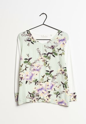 Long-sleeve floral blouse with pastel purple and yellow flowers and green leaves on a light mint background, hanging on a black hanger.