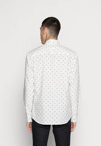 Camicia bianca a maniche lunghe con un sottile motivo geometrico ripetuto in grigio chiaro. Tessuto morbido con colletto alla francese e orlo curvo.