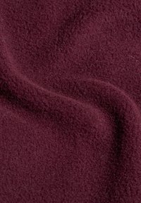 Burgundowa tkanina polarowa o miękkiej, teksturowanej powierzchni, o delikatnym połysku i gładkim opadająciu, odpowiednia do odzieży lub koców.