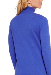 Maglione blu a collo alto realizzato in tessuto a maglia fine, con colletto alto e maniche lunghe, caratterizzato da una texture liscia e morbida.