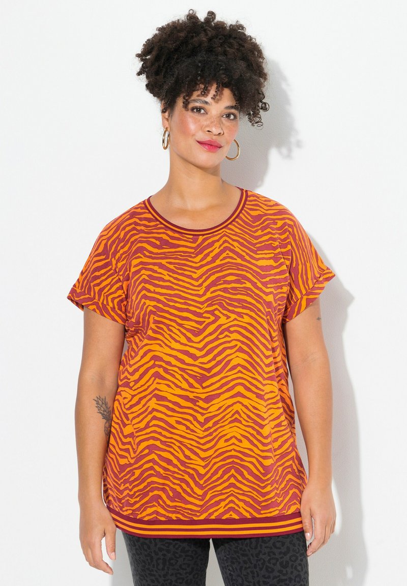Camiseta de manga corta en color naranja con un patrón de rayas de cebra en rojo oscuro y amarillo. Presenta un escote redondo y un dobladillo acanalado.